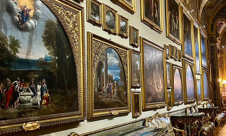 Interior gallery wall of the Borghese Gallery in Rome, filled with framed Renaissance and Baroque paintings in ornate golden frames.