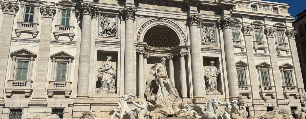 Detail of the Trevi Fountain in Rome, featuring Baroque sculptures of Neptune, horses, and sea creatures against the ornate façade.