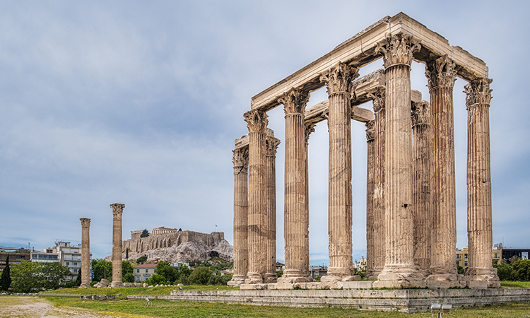 Ruins of the Roman Forum in Rome, with ancient stone columns and remnants of temples against a backdrop of the city.