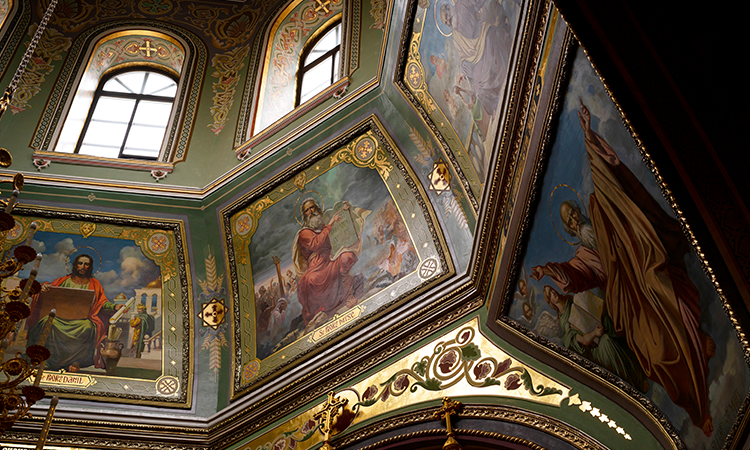 Interior of the Sistine Chapel with Renaissance frescoes on the ceiling and walls, depicting biblical scenes and figures in vivid color.