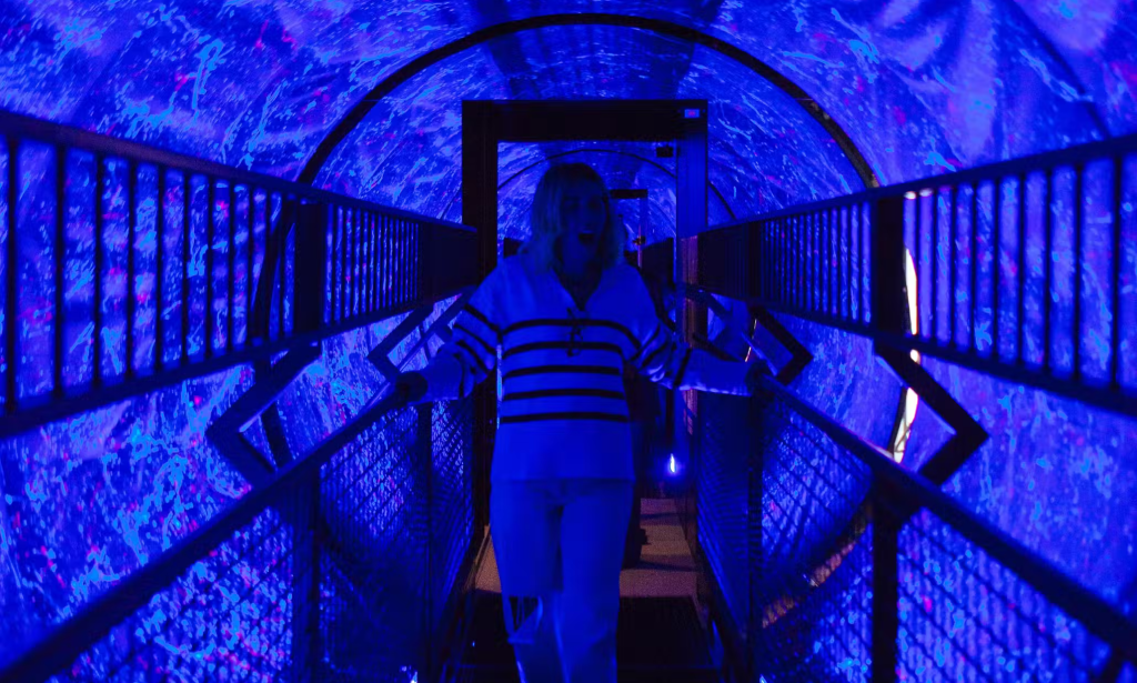 Visitor walking through a rotating tunnel illuminated with blue and purple lights at the Museo delle Illusioni in Rome.